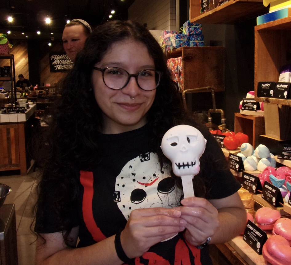 Jizelle Villegas smiles while holding hold a skull-shaped bathbomb in Lush.